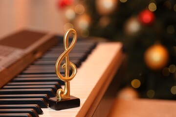 Golden treble clef on piano against blurred Christmas lights, closeup. Bokeh effect