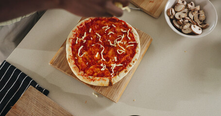 Hands, person and cooking pizza at house with meal prep, organic ingredients and healthy food. Above, chef and cheese toppings for Italian cuisine, vegetables and culinary skills for homemade lunch