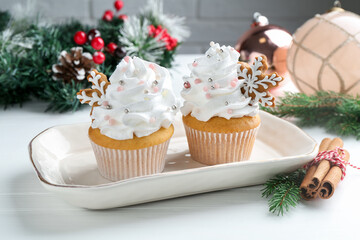 Tasty cupcakes with Christmas decor and cinnamon on white wooden table, closeup