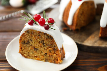 Piece of delicious Christmas cake with icing, cranberries and rosemary on wooden table, closeup