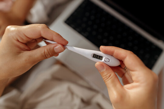 Hands holding digital thermometer close up for healthcare and illness