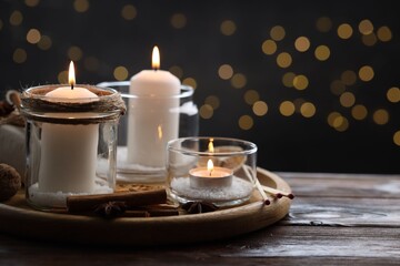 Christmas lanterns, matches and spices on wooden table against dark background with blurred lights, space for text. Bokeh effect