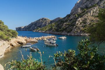 MARSEILLE, FRANCE &ndash; JULY 27, 2025: Tourists relax on the rocks and boats are moored in the clear turquoise water of the Calanque de Sormiou, a famous limestone inlet in the Calanques National Park.