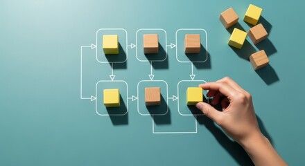 Hand completing a flowchart of colorful wooden blocks on a blue background