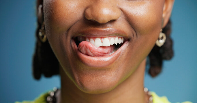 Dental, lick and teeth with black woman in studio for hygiene results or oral care satisfaction. Dentistry, mouth and tongue with happy African person on blue background for cleaning or whitening