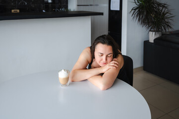 Beautiful young woman drinking cappuccino in her kitchen