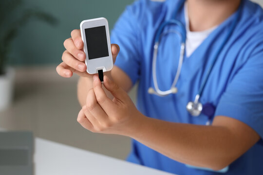 Male doctor with glucometer in clinic, closeup