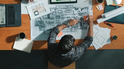 Top down view of civil engineer handed document while looking at blueprint. Aerial view of...