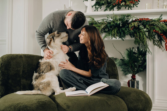 Couple cuddling dog relaxing during christmas holiday - Powered by Adobe