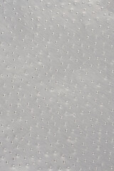 An extreme close-up of a silver aluminum foil surface, featuring a dense, repeating pattern of...