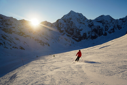 Skier on ski slope sunset view, popular winter holiday destination in Sulden, Italy