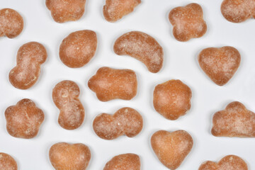 A full-frame, overhead view featuring a random pattern of baked, unglazed gingerbread cookies in various irregular and heart shapes on a white background