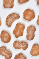 A vertical, full-frame background pattern created by several small, baked gingerbread cookies in various irregular shapes on a white surface