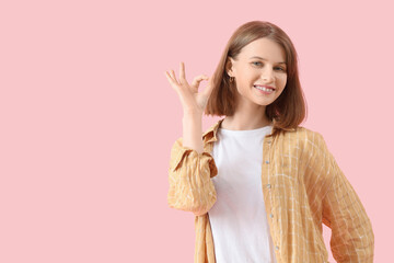 Young woman showing OK on pink background