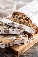 Traditional Christmas Stollen with Raisins and Powdered Sugar on wooden table. Close up