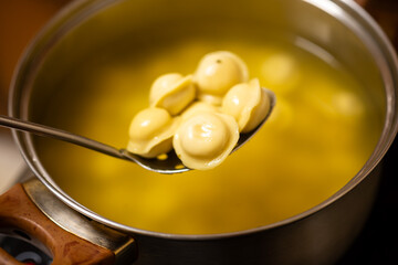 Spoon with Boiled Dumplings Over Pot of Broth