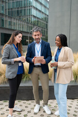 Fototapeta premium Diverse business team discussing data on tablet outdoors
