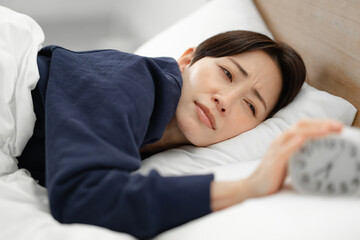 ベッドで寝る女性　アラーム　寝坊