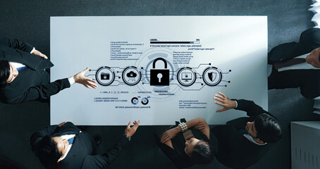 A professional business team collaborates to discuss data security strategy using a digital interface on a modern office table, highlighting teamwork and innovation. Trope