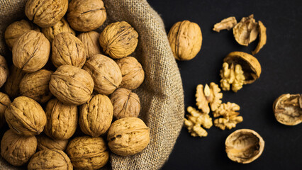 A lot of walnuts in shells in burlap on a dark background. The best source of strength, energy and vitamins for a healthy diet
