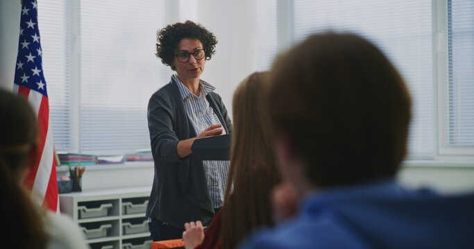 Enthusiastic Smiling Woman Explains Concept Students During Interactive Classroom Discussion. Innovative US Education System, Active Learning, Student Participation, Communication Based Teaching.