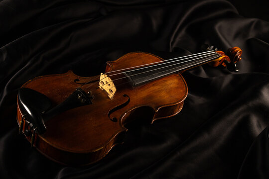 vieux violon pos&eacute; sur une table recouverte d'un tissu noir