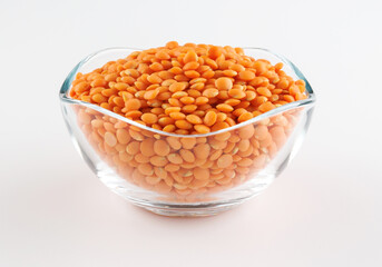 Glass cup with red lentils on white background. Side view.