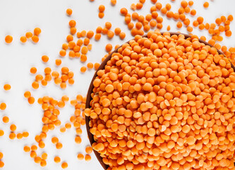 Clay cup with red lentils and lentils scattered around on white background. Top view .