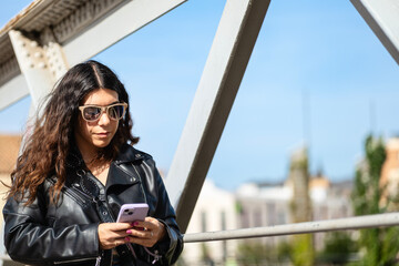 Young woman looking at her cell phone on an urban bridge