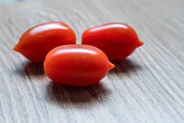 Tiny cherry tomatoes (ciliegini, pachino, cocktail). group of cherry tomatoes on awooden table and blur background. ripe and juicy cherry tomatoes