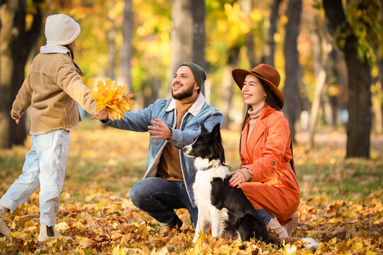 Happy parents with their daughter and dog in autumn park - Powered by Adobe