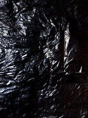 Close-up of Crumpled Black Plastic Bag Texture with Highlights