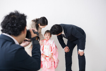 室内で七五三や記念日のファミリーフォトを撮影をする家族とカメラマン