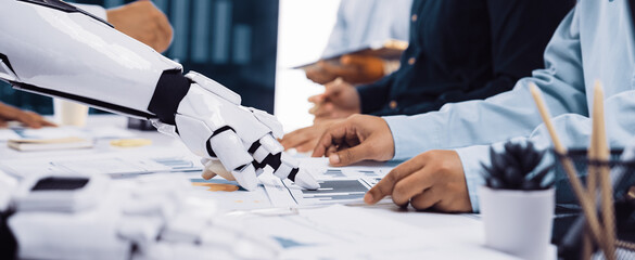 A futuristic scene in a business meeting where a robotic arm interacts with human hands,...