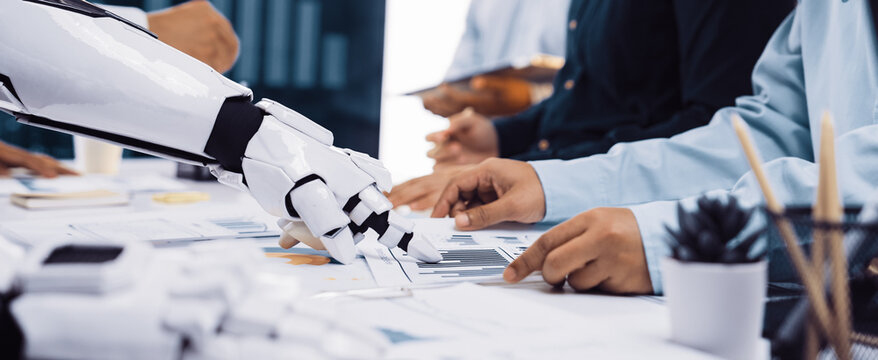 A futuristic scene in a business meeting where a robotic arm interacts with human hands, highlighting advancements in technology and corporate collaboration.Noogenesis