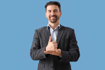 Young businessman using sign language on blue background