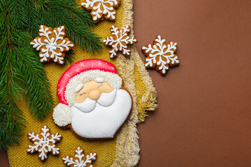 Tasty gingerbread cookies and fir tree branches on brown background, flat lay with space for text. Christmas treat