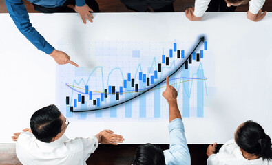A diverse team of professionals engages in a strategic analysis of financial data, reviewing charts and graphs to devise plans for business growth and success. Axiom