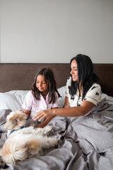 A woman and a child are laying on a bed with a dog