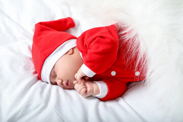 Cute newborn baby in Christmas costume sleeping in bed at home, above view
