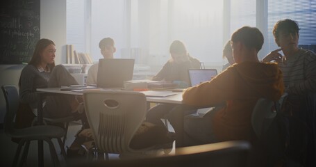 Diverse Group of Students Gathers Around Central Table, Working Together Intensely on Laptops. Collaboration, Group Project Work, and Essential Role of Digital Learning in Modern Educational Setting.