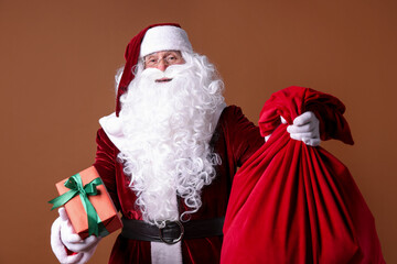 Santa Claus with red bag and Christmas gift on brown background