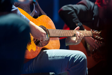 Male musician performing on stage and playing electric guitar during a live concert show with stage lights and sound equipment