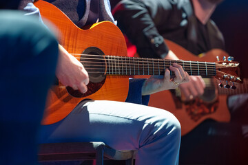 Male musician performing on stage and playing electric guitar during a live concert show with stage lights and sound equipment