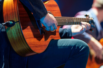 Male musician performing on stage and playing electric guitar during a live concert show with stage lights and sound equipment