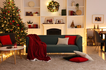 Stylish room with Christmas tree, sofa, fireplace and festive decor. Interior design