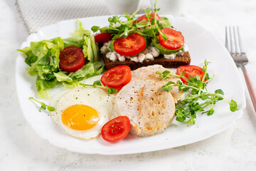 English breakfast. Fried egg, chicken meatloaf and sandwich with tomatoes, avocado and cheese.