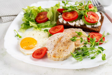English breakfast. Fried egg, chicken meatloaf and sandwich with tomatoes, avocado and cheese.