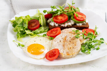 English breakfast. Fried egg, chicken meatloaf and sandwich with tomatoes, avocado and cheese.