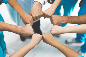 Doctor and interns holding fists together indoors, closeup